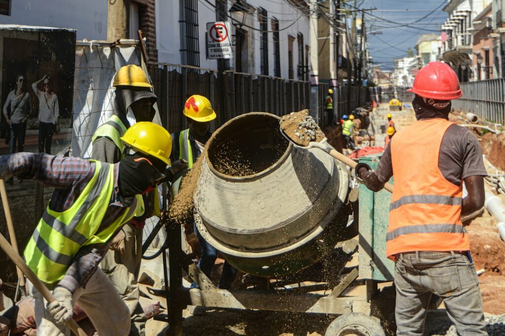 Construction workers operating a small concrete mixer on a building site