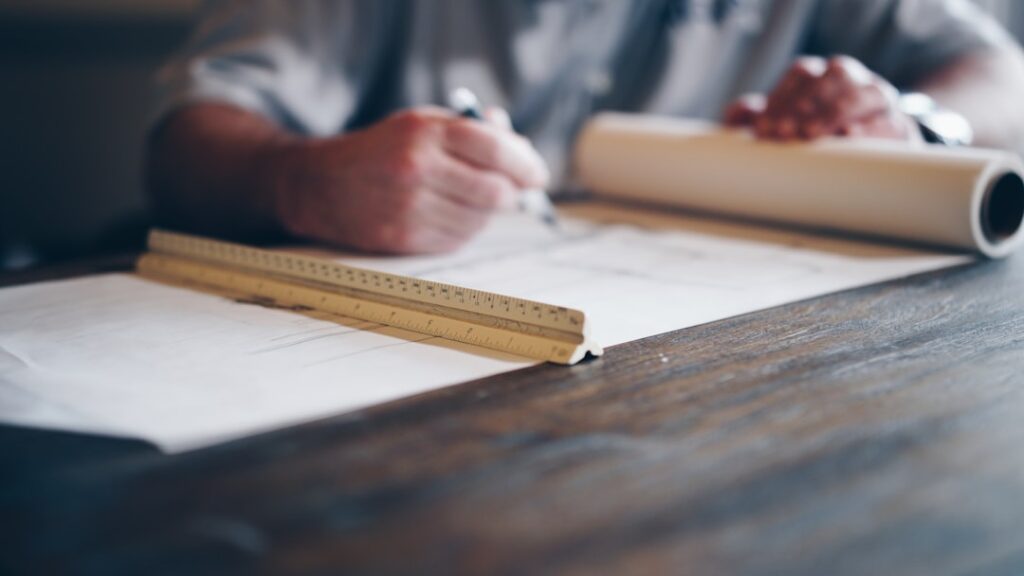 Person drafting material takeoff on a building blueprint