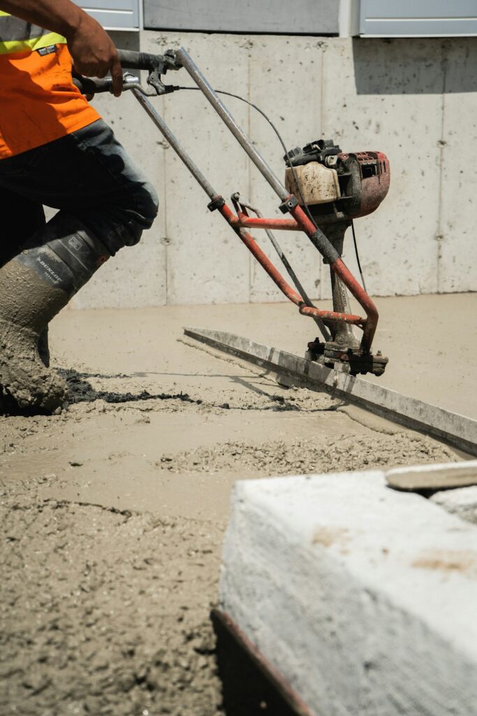 Worker using equipment during a concrete pour on a construction site